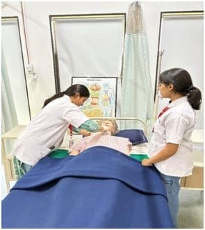 Students practising bedside care on a training mannequin
